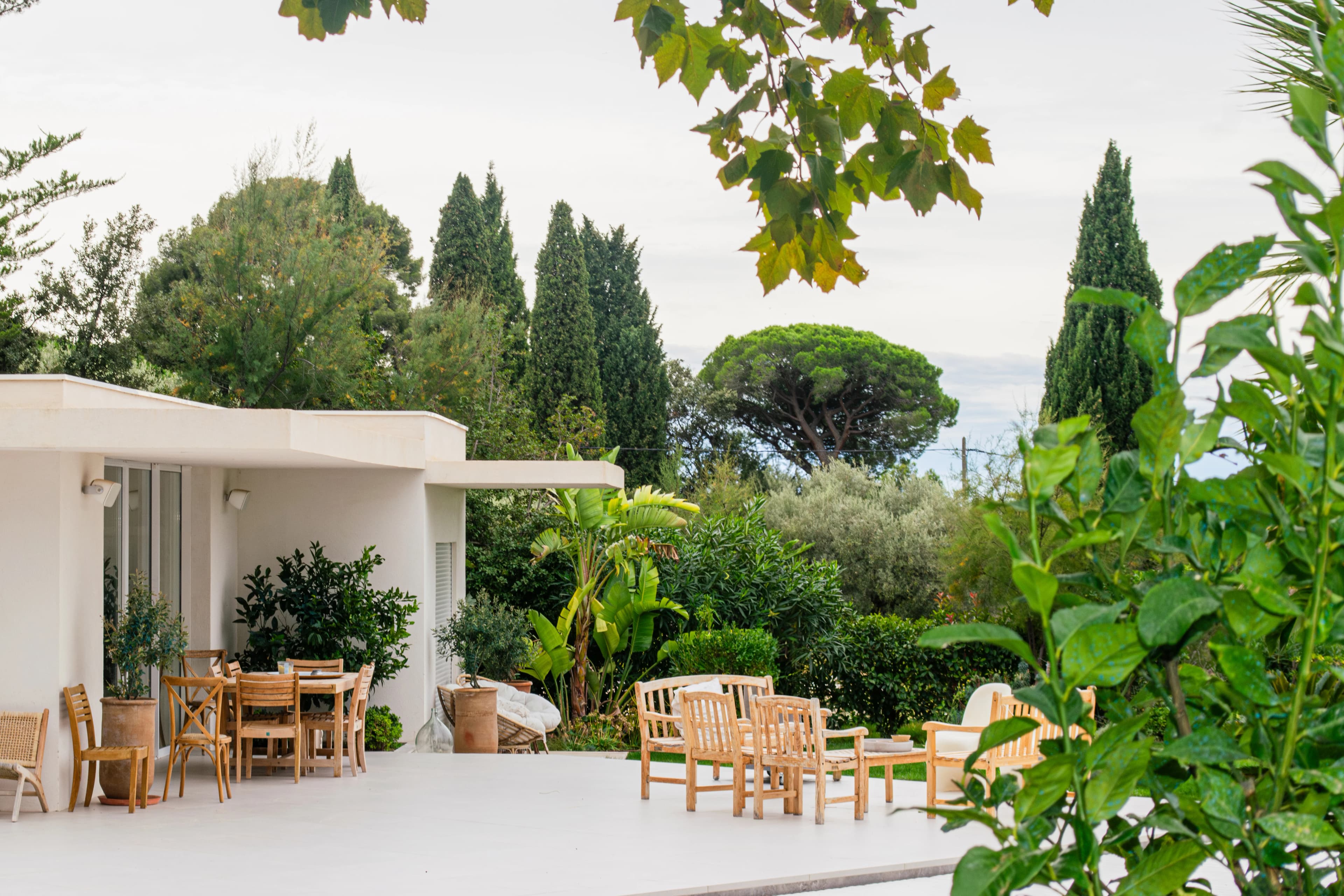 Terrasse moderne entourée de verdure et de grands arbres.